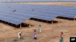 Indian laborers work near solar panels at the Gujarat Solar Park at Charanka in Patan district, about 250 kilometers (155 miles) from Ahmadabad, India, Apri. 14, 2012. 
