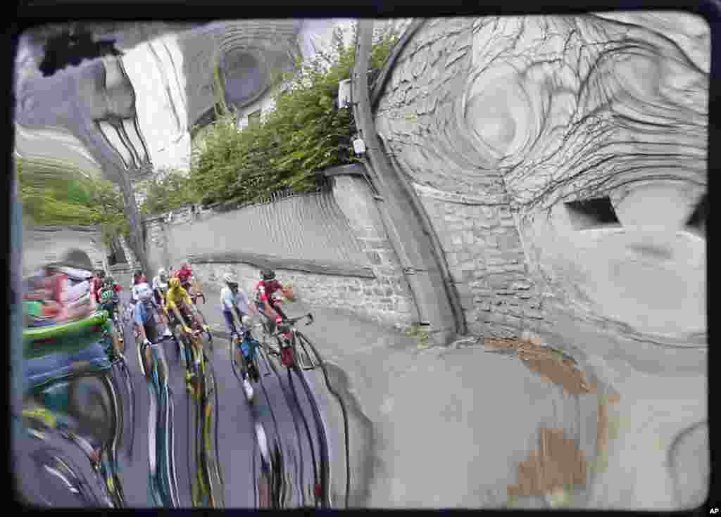 The pack with Britain's Chris Froome, wearing the overall leader's yellow jersey, is reflected in a roadside mirror during the 21st stage of the Tour de France cycling race over 113 kilometers (70.2 miles) with start in Chantilly and finish in Paris, France.