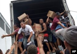 People loot a truck allegedly set on fire by drug traffickers in Rio de Janeiro, Brazil, Tuesday, May 2, 2017. Several public buses and cargo trucks were torched in Rio de Janeiro on Tuesday.