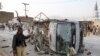 A Pakistani police officer walks past a police vehicle targeted by a suicide bomber in Quetta, April 24, 2018.