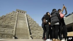 Students take pictures of themselves in front of a mock pyramid during the countdown to when many believe the Mayan people predicted the end of the world, Friday, Dec. 21, 2012, in Taichung, southern Taiwan.
