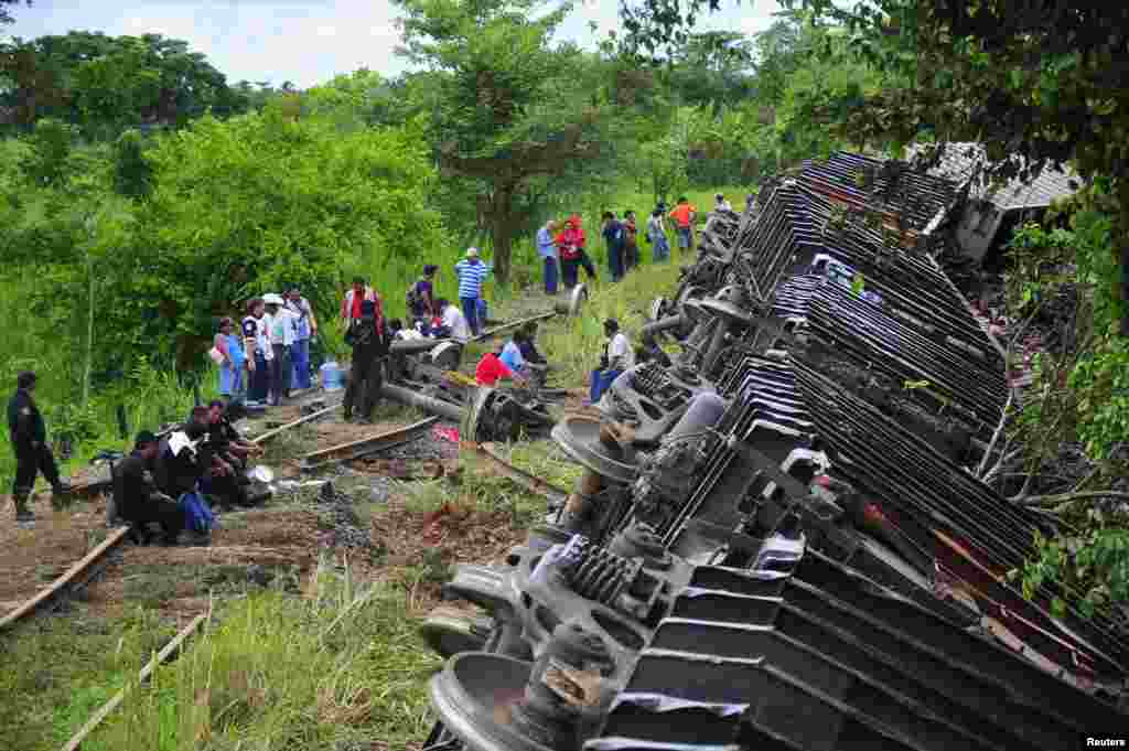 Para polisi dan petugas penyelamat berdiri di samping gerbong kereta api yang tergelincir di Huimanguillo, di negara bagian Tabasco, Meksiko.