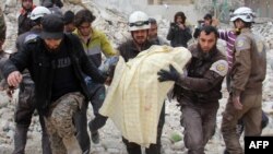Des membres de la défense civile syrienne, connus sous le nom de Casques blancs, retirent une victime des décombres d'un bâtiment détruit suite à une attaque aérienne à Idlib, Syrie, 15 mars 2017