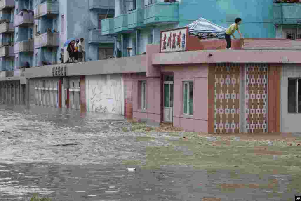 Warga menunggu di atas atap bangunan yang terendam banjir di Anju City, provinsi Phyongan, Korea Utara (30/7).