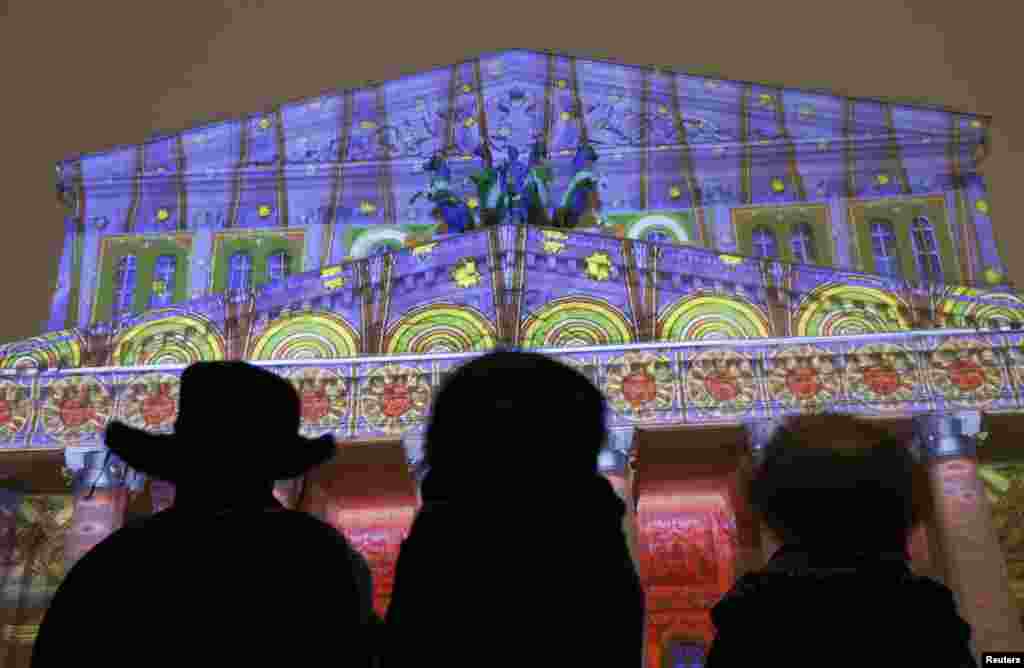 Orang-orang melihat pameran cahaya dalam pagelaran " Kota Bidadari " yang didasarkan pada hiasan dan karya seni Rusia di Teater Bolshoi di Moskow. 