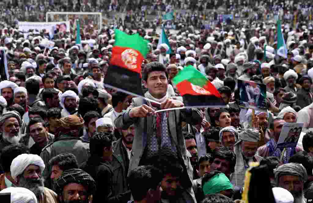 Seorang pendukung kandidat presiden dan mantan menteri luar negeri Zalmai Rassoul (tengah) melambai-lambaikan dua bendera nasional Afghanistan dalam sebuah kampanye pemilu di Herat (30/3). (AP/Massoud Hossaini)
