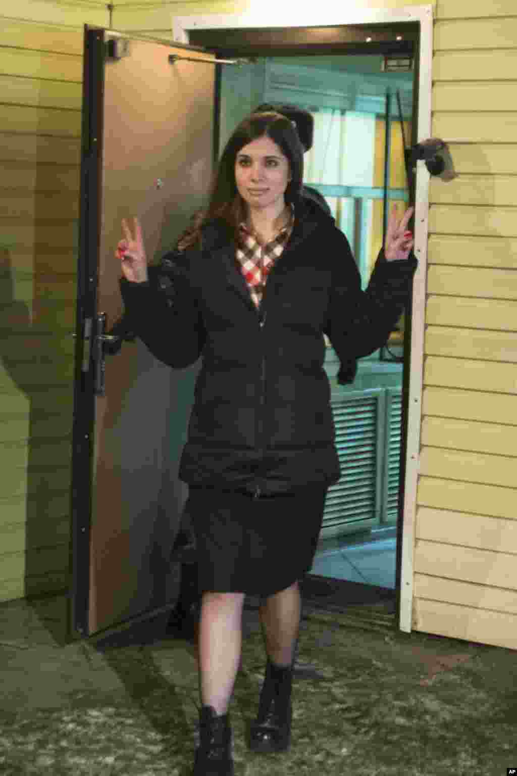 Nadezhda Tolokonnikova mengacungkan jari tanda damai saat ia meningalkan penjara di Krasnoyarsk, Rusia, Senin (23/12). (AP/Tatyana Vishnevskaya)