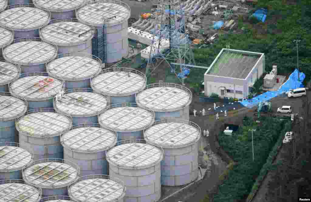 Foto dari udara menunjukkan para pekerja menggunakan baju dan masker pelindung di atas tangki-tangki penyimpan air berkontaminasi di PLTN Fukushima (20/8). (Kyodo)