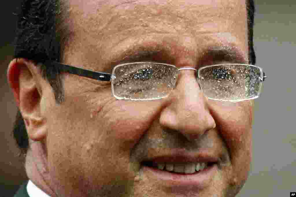 Hollande smiles from his car during a rain shower on the Champs Elysees.