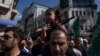 Palestinska devojčica sa plastičnom puškom na očevima ramenima tokom protesta u Ramali na Zapadnoj obali (Foto: AP/Nasser Nasser)