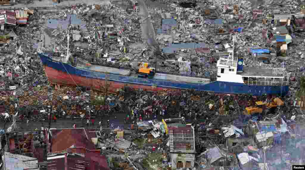 Warga melihat kapal yang tersapu badai topan Haiyan, di pusat kota Tacloban di Filipina tengah, 21 November 2013.