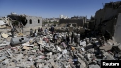 People stand amidst the rubble of houses destroyed by an overnight Saudi-led air strike on a residential area in Yemen's capital Sanaa, May 1, 2015. 