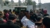 Police officers move the body of a colleague who was killed in an attack on a police station, at a hospital in Dera Ismail Khan, Pakistan, on Feb. 5, 2024.