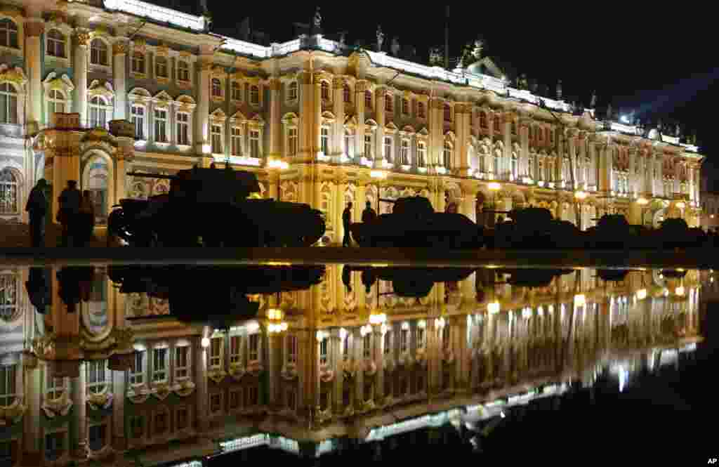 People walk past World War II tanks early in the morning — at the time the Nazi Germany attacked the Soviet Union 75 years ago — at Dvortsovaya (Palace) Square in St. Petersburg, Russia, with Zimny (Winter) palace in the background.