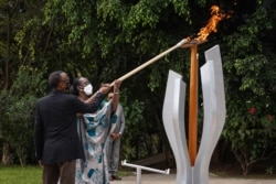 Rais wa Rwanda Paul Kagame (L) na mkewe Jeannette Kagame (R) wanawasha moto wa kumbukumbu ya miaka 27 ya Mauaji wa Kimbari yaliyotokea mwaka 1994 dhidi ya Kabila la Watutsi katika kituo cha kumbukumbu cha Kigali Genocide Memorial, Kigali, Rwanda, Aprili 7, 2021. (Photo by Simon Wohlfahrt / AFP)