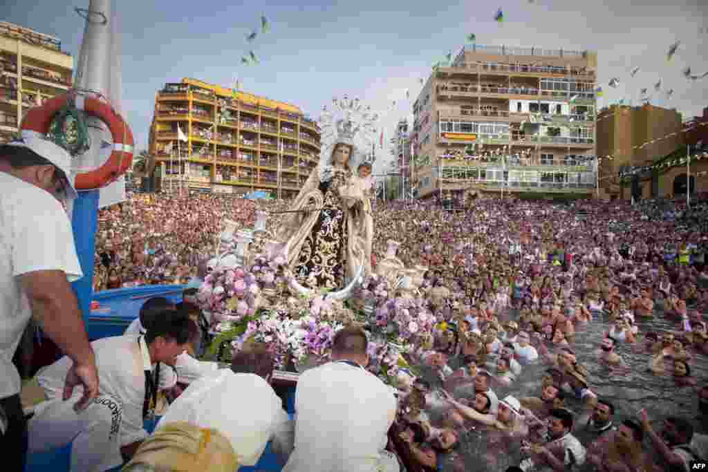 Penitents carry a statue of the Virgen del Carmen, the patron saint of fishermen, onto a boat at the Puerto de la Cruz on the Spanish Canary island of Tenerife, July 12, 2016.