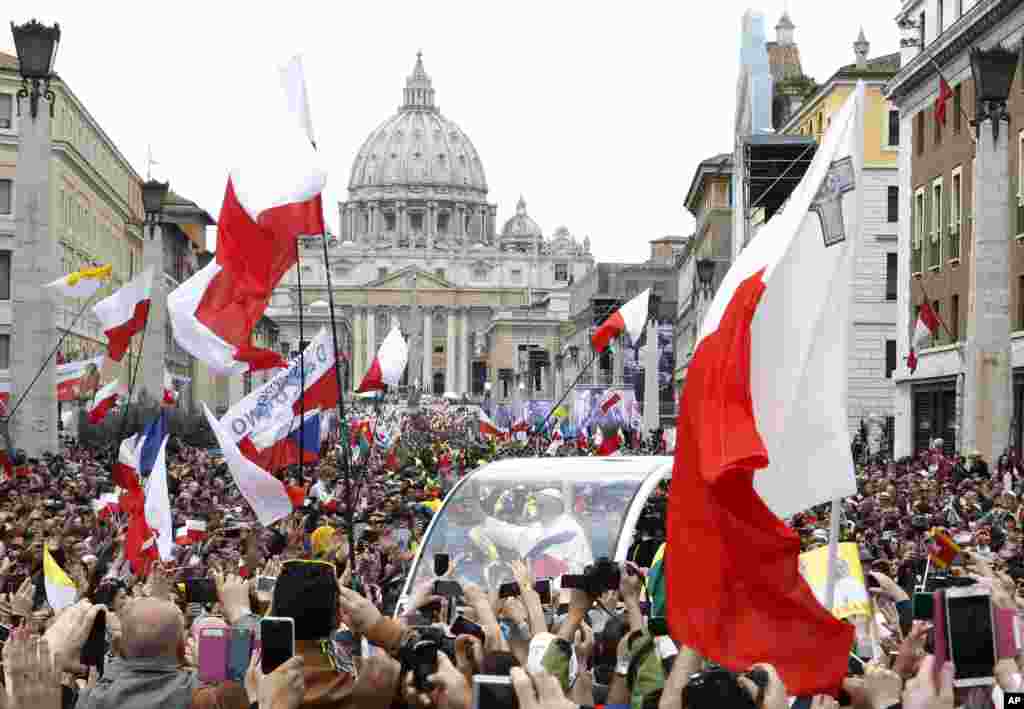 Paus Fransiskus menyapa umat ketika melewati kerumunan sepanjang jalan Via della Conciliazione untuk merayakan upacara kanoninasi Paus Yohanes ke-23 dan Paus Yohanes Paulus ke-2 di Lapangan Santo Petrus, di Vatikan, 27 April 2014.