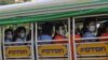 Factory workers wearing protective face masks and shields ride a truck as they go to their works in Hlaing Tharyar Industrial Zone on Oct. 12, 2020, on the outskirts of Yangon, Myanmar. 