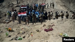 Des soldats irakiens devant la tombe commune des soldats chiites du camp de Speicher qui ont été tués par les soldats du groupe islamique à Tikrit, le 6 avril 2015.