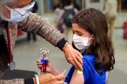 Jehna Kottori, 10, dari Worcester, Mass., kanan, bersiap untuk menerima suntikan vaksin Pfizer COVID-19, 2 Desember 2021, di klinik vaksinasi keliling, di Worcester. (Foto: AP)