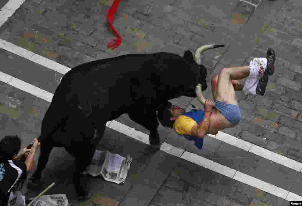 Seorang pelari yang ditanduk oleh adu banteng El Pilar di jalan Estafeta dalam acara festival kejar banteng San Fermin festival in Pamplona, Spanyol, 12 Juli 2013.