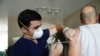 FILE - Ledsiel Garcia, a pharmacy technician with DeliveRxd Pharmacy in Tampa, administers the Pfizer-BioNTech vaccine to Mike Payne, a federal employee, at his home in St. Petersburg, Fla., July 30, 2021.