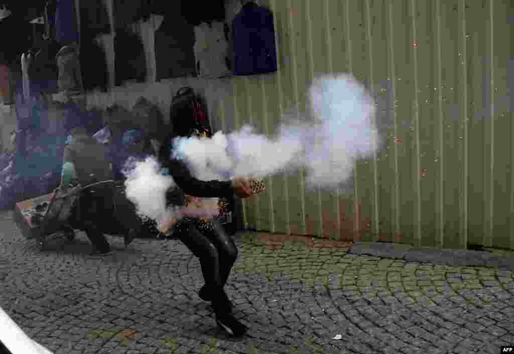 Seorang demonstran mahasiswa etnis Kurdi melemparkan mercon ke arah polisi anti huru-hara saat aksi protes di pusat kota Istanbul, Turki. 