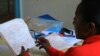 Benedetta Kamene, Volunteer Children's Officer, reviews a stack of newly-issued birth certificates at the Kimadzo community-based organization, Kwale, Kenya, July 25, 2012. (VOA/Jill Craig)