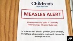 In this May 2, 2017 photo, a sign at the specialty clinic at Children's Minnesota in Minneapolis, alerts patients to a measles outbreak in the area. 