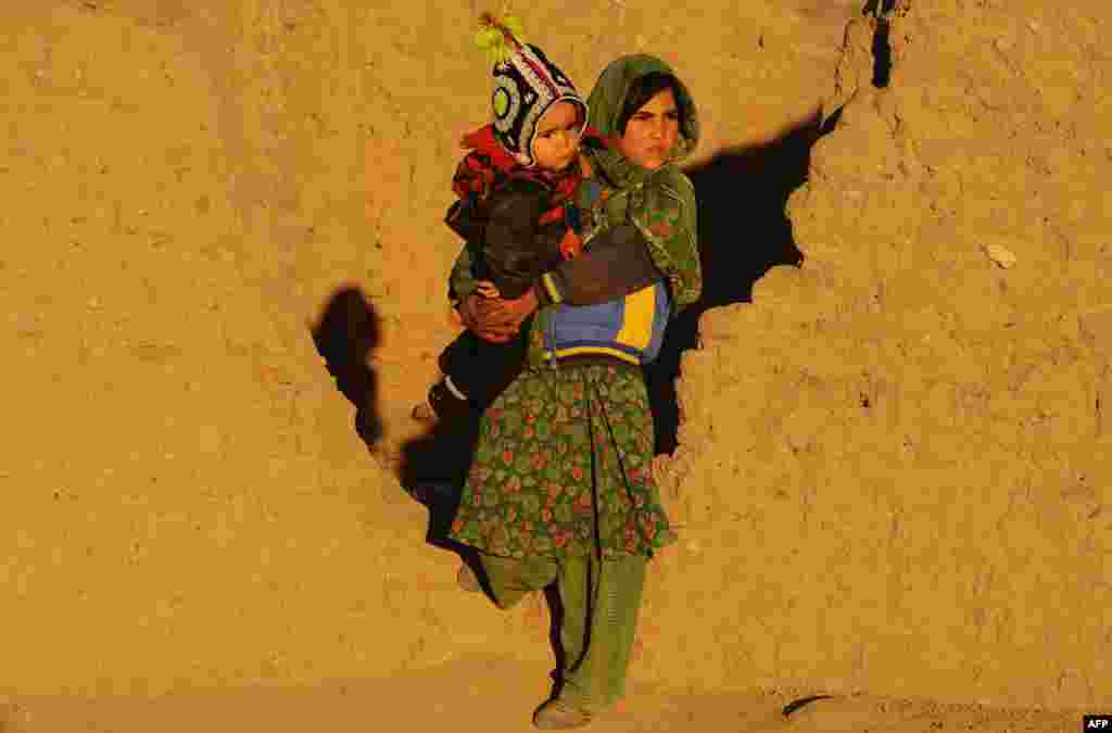 Seorang perempuan Afghanistan menggendong bayi di pinggiran kota Herat, Afghanistan selatan. 