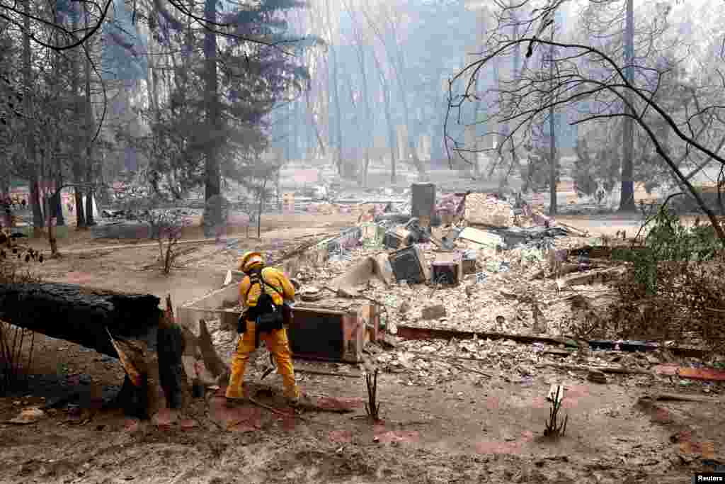 A firefighter extinguishes a hot spot in a neighborhood destroyed by the Camp Fire in Paradise, California, U.S., Nov. 13, 2018. 