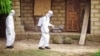 FILE - A healthcare worker in protective gear sprays disinfectant around the house of a person suspected to have the Ebola virus in Port Loko Community, situated on the outskirts of Freetown, Sierra Leone, Oct. 21, 2014. 