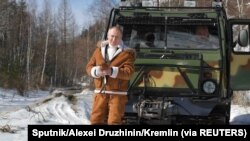 Le président russe Vladimir Poutine se tient devant un véhicule avec le ministre de la Défense Sergei Shoigu dans la taïga en Sibérie, le 21 mars 2021.