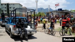 Des habitants regardent un policier passé lors d'une opération anti-drogues dans la favela de la Cité de Dieu à Rio de Janeiro, Brésil, le 20 novembre 2016.