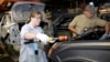 FILE - A female employee works alongside a male colleague at a Ford Motor Plant in Wayne, Michigan.
