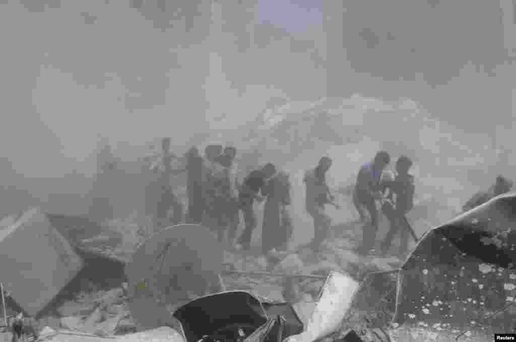 Orang-orang membantu mengevakuasi warga sipil di sebuah wilayah yang menurut para aktivis disebabkan oleh serangan pasukan-pasukan pendukung Presiden Suriah Bashar al-Assad di distrik Bustan al-Qasr, Aleppo.