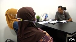 “Noradhiah” and “Shahirah” listen and watch the Muslim Consumer Association Malaysia hold a phone call to start a negotiation with a loan shark’s henchman. (Dave Grunebaum/VOA)