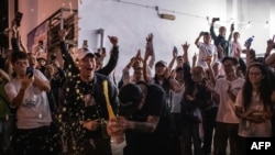 A pro-democracy supporter (C) opens a bottle of champagne outside a polling station to celebrate after a pro-Beijing lost a seat in district council elections, in Hong Kong, early Nov. 25, 2019. 