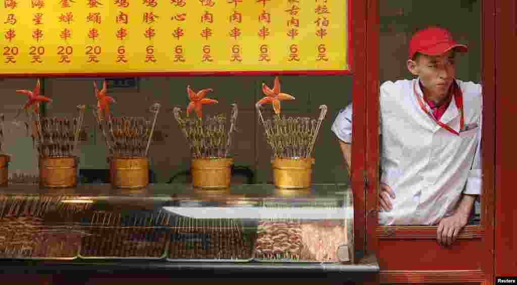 Seorang pemilik vendor makanan menunggu datangnya pelanggan di sebuah distrik perbelanjaan di Beijing, China.