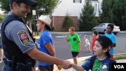 A boy shakes the hand of police officer Anthony Patalena in Fairfax Country, Virginia, Aug. 2, 2016. (D. Block/VOA)