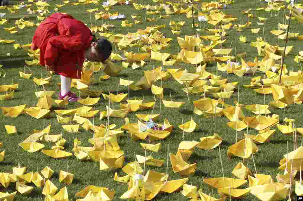 A girl reads massages written on paper ships for the victims of the sunken ferry Sewol at a group memorial altar in Seoul, South Korea.