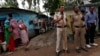 Police stand guard as residents (L) look on at the Ravidas camp, the slum where three of the four men convicted of raping and murdering a 23-year-old woman in Delhi reside at, in New Delhi, September 13, 2013.