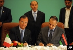 Le ministre italien des Affaires étrangères, Franco Frattini ( à gauche) signant un mémorendum d'entente avec le chef de la diplomatie des rebelles libyens, Ali al-Essawi , à Benghazi