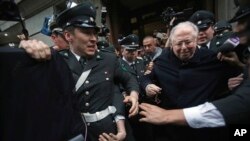 FILE - The Rev. Fernando Karadima, center, is escorted from court after testifying in a lawsuit brought by three of his victims alleging sex abuse cover-up by the Archdiocese of Santiago, Nov. 11, 2015. 