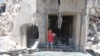 FILE - A boy stands at a site hit by a barrel bomb in the rebel-held area of Old Aleppo, Syria, July 11, 2016.