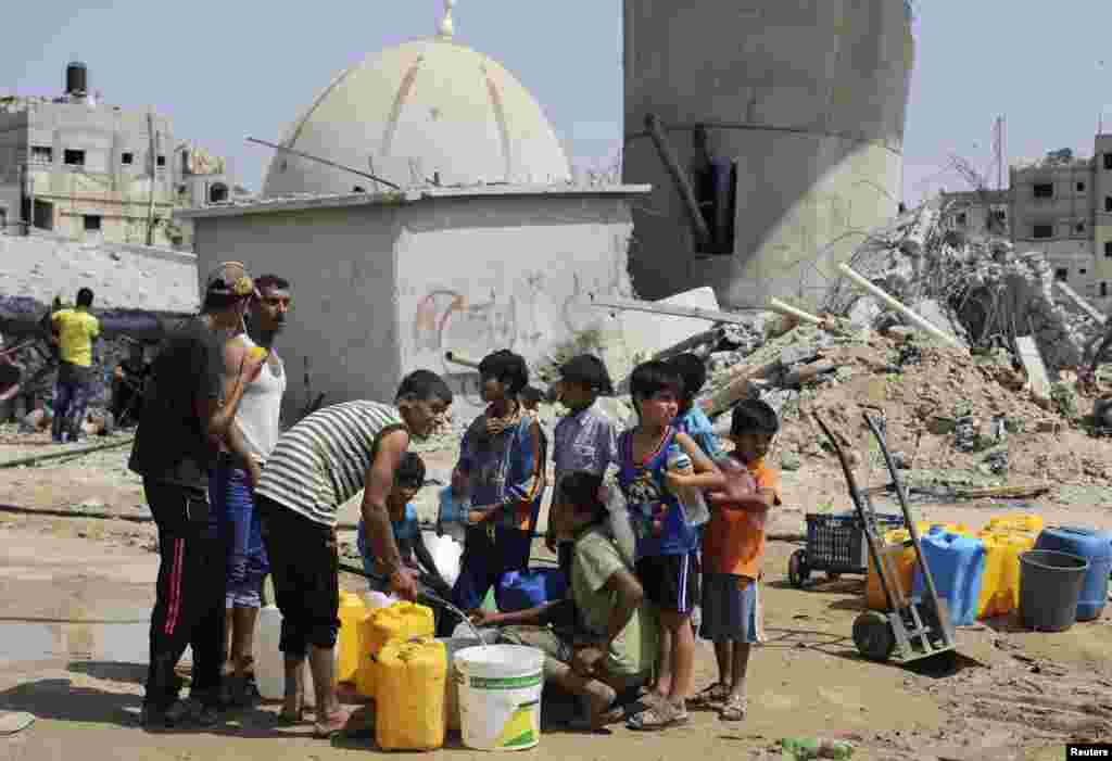 Anak-anak mengumpulkan air dalam gencatan senjata lima hari di Khan Younis di Jalur Gaza selatan, 14 Agustus 2014.