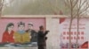 FILE - A farmer walks past propaganda depicting ethnic minority residents reading the constitution with slogans which reads, "Unity Stability is fortune, Separatism and Turmoil is misfortune," near Kashgar in China’s Xinjiang Uyghur Autonomous Region on March 19, 2021.