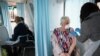 A woman receives a dose of the Oxford-AstraZeneca COVID-19 vaccine inside a mobile vaccination center for the COVID-19, in Thamesmead, London, Feb. 14, 2021. 