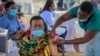 FILE - A woman receives a coronavirus vaccination at the Kololo airstrip in Kampala, Uganda, May 31, 2021.