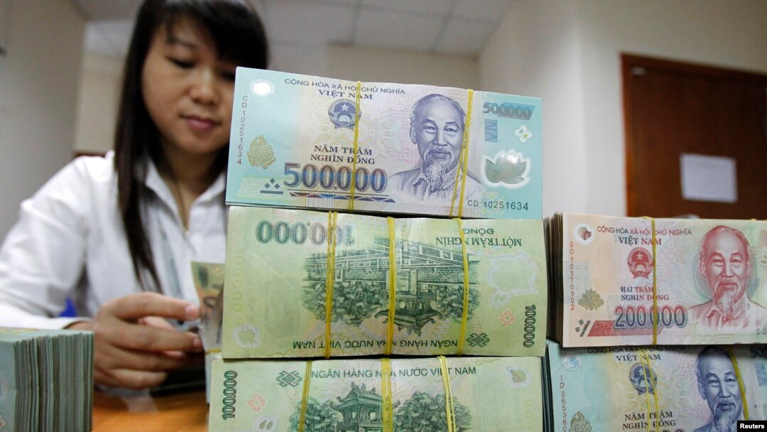 An employee counts Vietnamese dong banknotes at a counter of the Vietnam International Bank in Hanoi November 3, 2011. REUTERS/Kham (VIETNAM - Tags: BUSINESS)